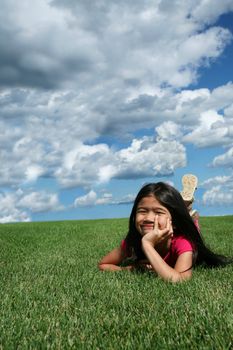 Little girl lying on grass in summer