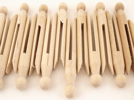 A tidy lineup of old fashioned clothespins isolated against a white background.