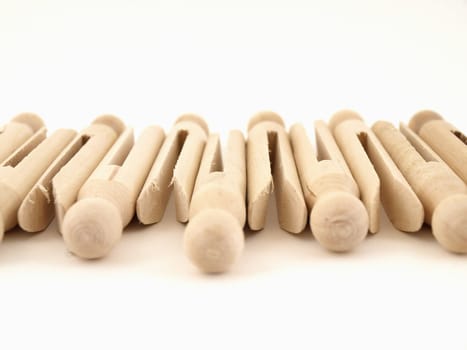 A tidy lineup of old fashioned clothespins isolated against a white background.