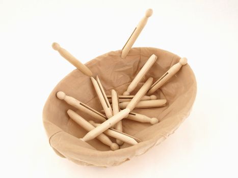 Old fashioned clothespins in a cloth covered basket isolated against a white background.