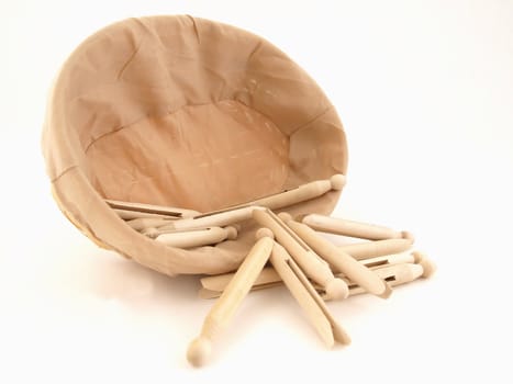 Old fashioned clothespins in a cloth covered basket isolated against a white background.