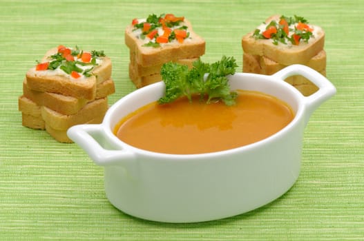 Bowl of vegetable soup with rusks on green background