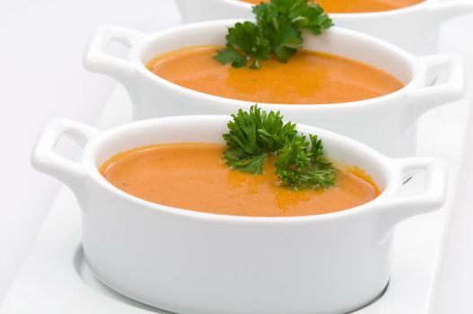 Ceramic bowls of vegetable soup with parsley on white