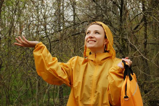 cheerful woman in orange raincoat enjoying rain