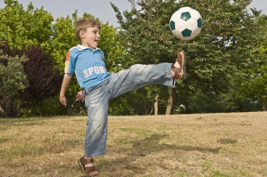 Game in football, the boy strikes very much on a ball on a children's soccer field