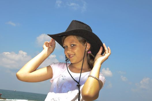 The girl happily smiles, tries on a hat and poses for the photographer