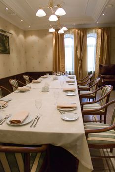 Table with chairs prepared for banquet in banquet-hall