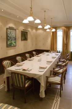 Table with chairs prepared for banquet in banquet-hall