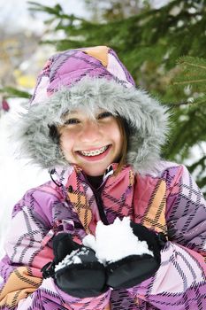 Portrait of happy teenage girl holding snow in gloves