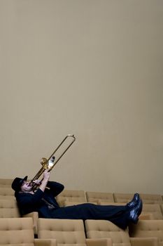 A trombonist in a black suit and yellow background.