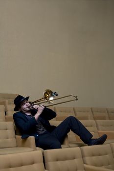 A trombonist in a black suit and yellow background.