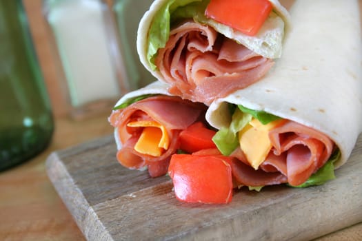 Close up of a ham and cheese wrap with the fixings.