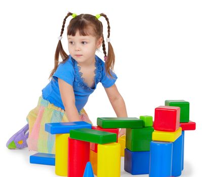 The little girl is playing with colored bricks