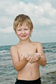 boy kept in the hands of marine sand, which is raised from the seabed