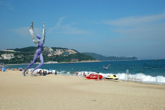 China South Sea, Guangdong province. Shenzhen city - sea side, wide beach at DaMeiSha. Large angels sculptures standing at the beach.