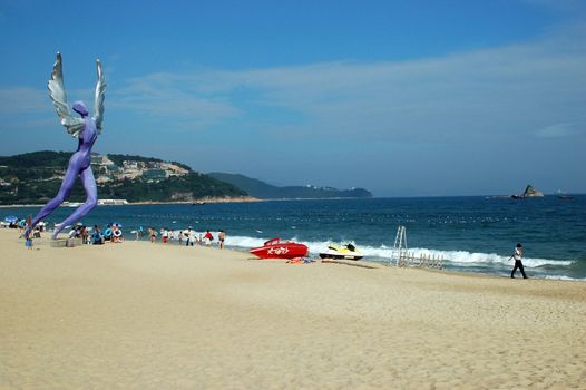 China South Sea, Guangdong province. Shenzhen city - sea side, wide beach at DaMeiSha. Large angels sculptures standing at the beach.