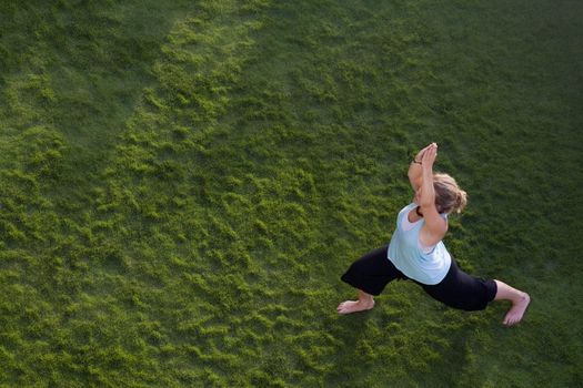 Woman doing yoga in the grass. Shot from above.