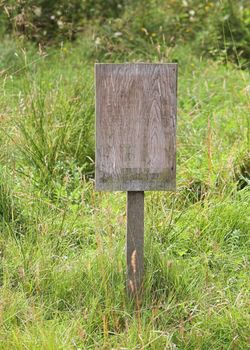 A blank wooden notice board in a meadow.