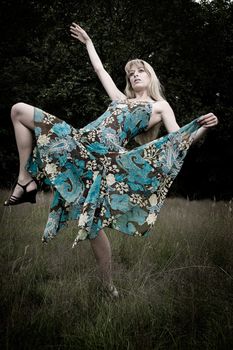 Young blond woman wearing a dress in the forest