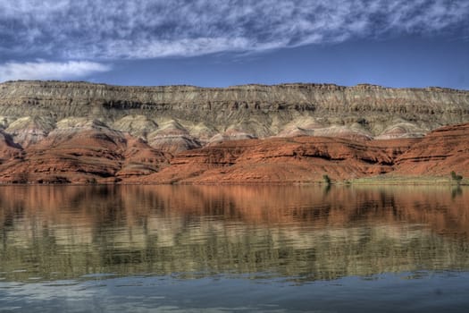 A desert lake reflecting the red rocks and blue sky.