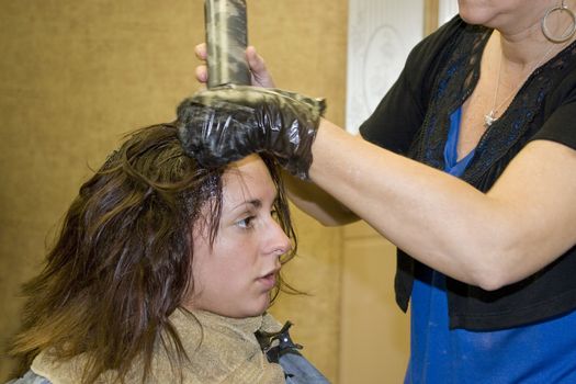 A hairdresser working on a clients hair color at the salon.