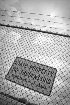 A no trespassing sign that reads STATE PROPERTY NO TRESPASSING outside an airport.