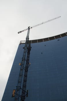 A glass building under construction with snow falling.