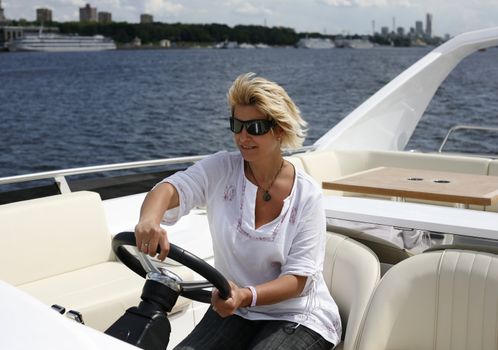 The adult woman behind a steering wheel of a yacht