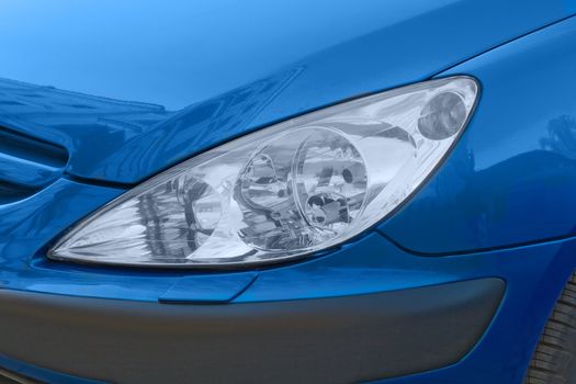 The headlight of a blue modern car