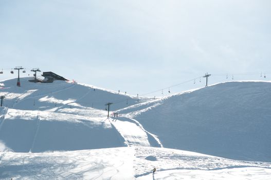 Pretty empty ski piste with chairlifts and station in the background - shot in Livigno, Italian Alps