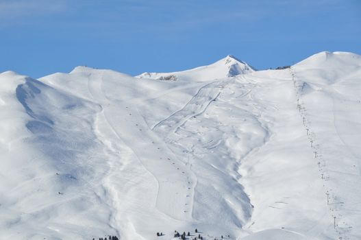 View on a steep skking mountain with two slopes, skiers and lifts - shot in Livigno, Italian Alps