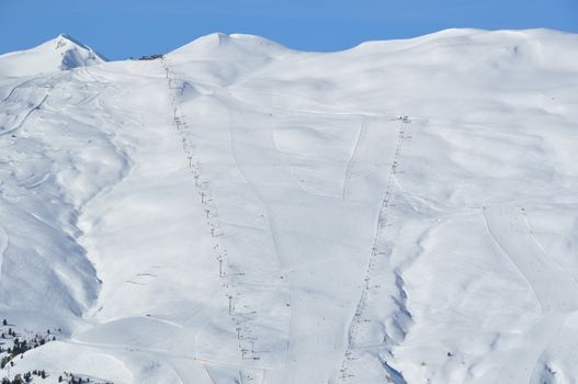 View on a steep skking mountain with two slopes, skiers and lifts - shot in Livigno, Italian Alps