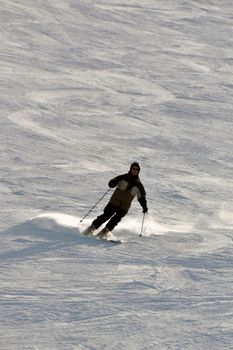 Middle aged female snowboarder wearing helmet and snow goggles in powder snow on steep hill - shot in Livigno, Italian Alps