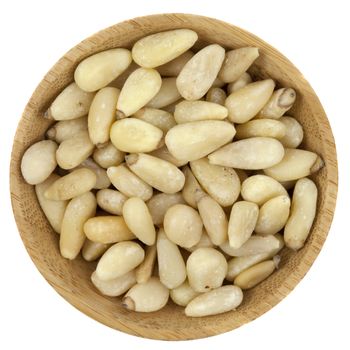 pine nuts on a small round wooden bowl isolated on white