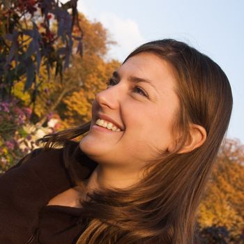 Head portrait of a happy young woman in an autumn park