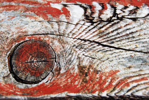 closeup of wood with a knothole and old red painting