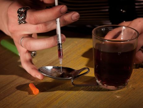 Closeup of woman's hand drawing black tar heroin into a needle