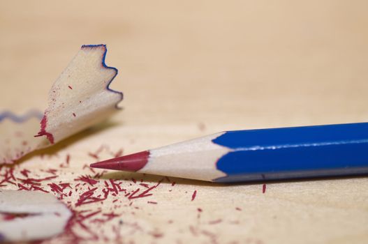 Sharpened pencil and wood shavings, on light color wood background