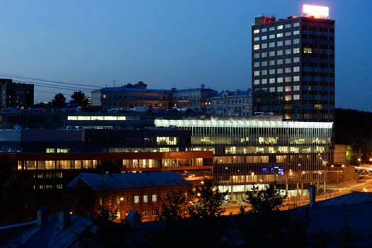 Modern office building locating among the old houses at night