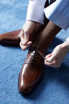 Businessman tying his shoes as he gets dressed for work.