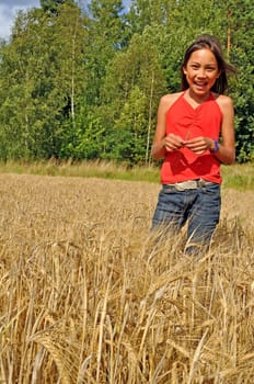 A young girl standing in a field of oats.