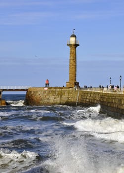 View of Whitby pier and lighthouse with surf