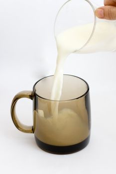 pouring creamy milk in a black glass