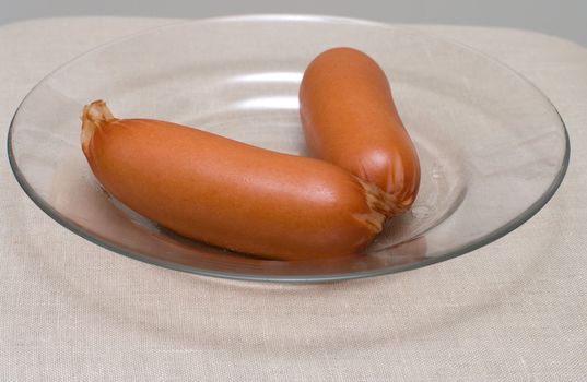 Two sausages on a transparent plate a close up.