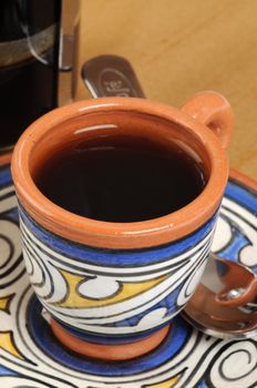 Cup of freshly brewed coffee in colorful pottery mug.