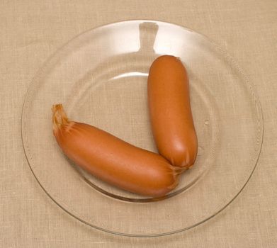 Two sausages on a transparent plate a close up.