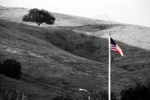 a grayscale coversion with the American flag re-colorized. Rolling hills in the background.