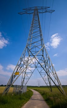 high voltage power tower in a rural farmlandscape with country road