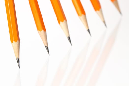 Few wooden yellow pencils standing in a row on white background