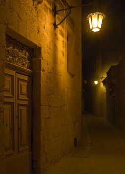 An old door in a dark alley lit by a lantern